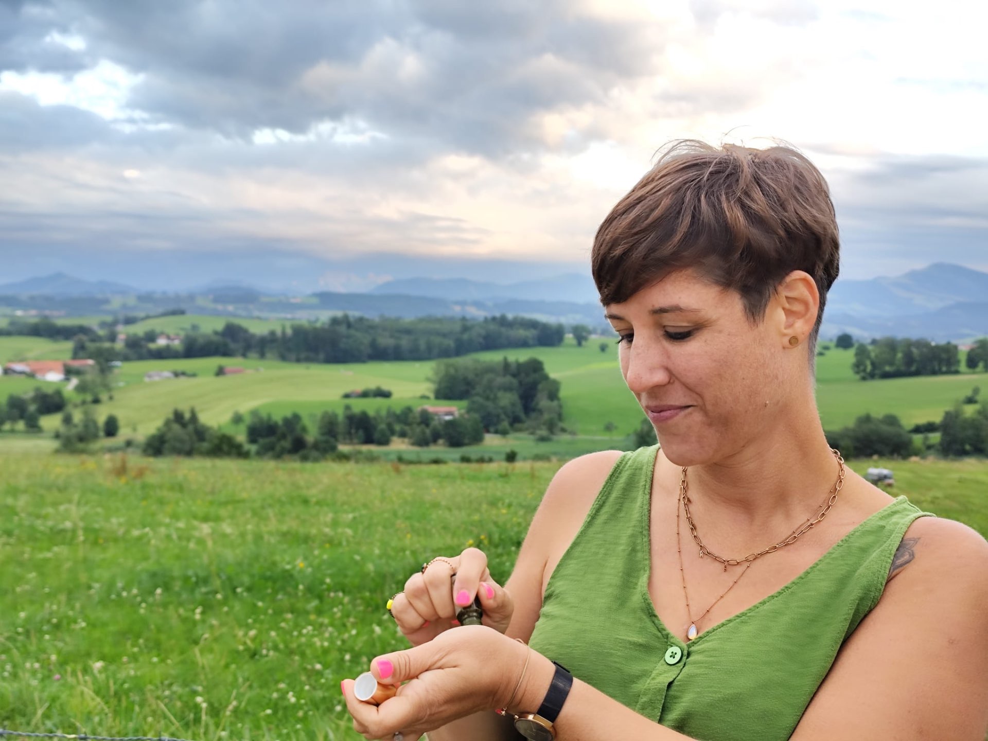 Steffi riecht an einem ätherischen Öl vor einer weiten Landschaft